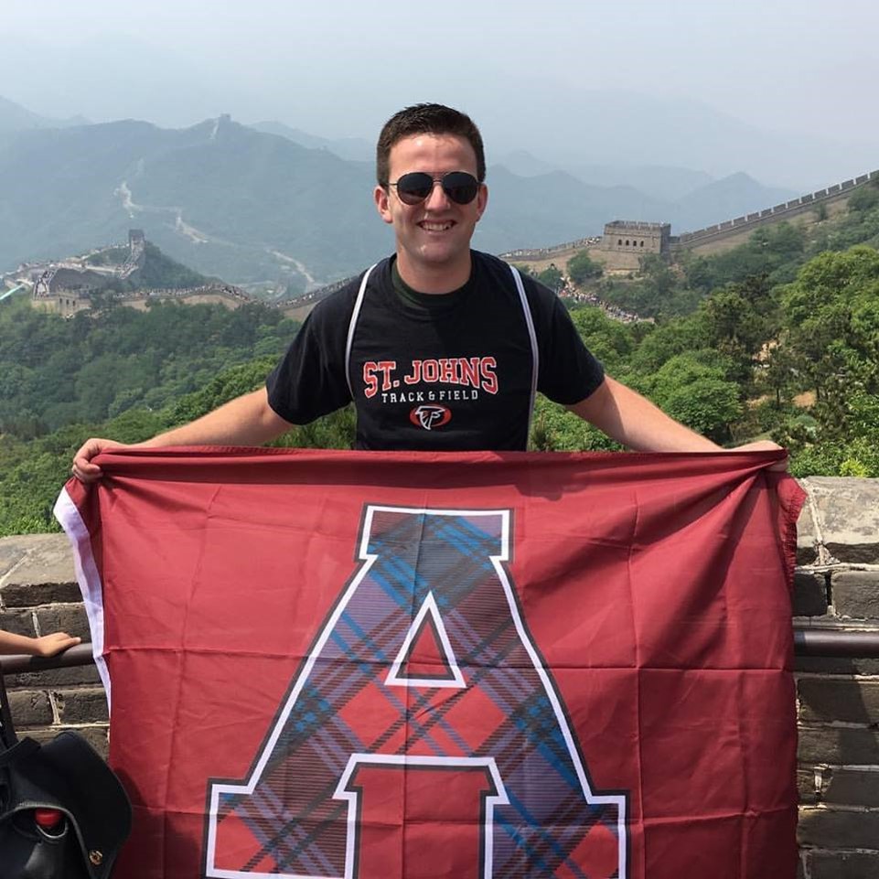 A photo of student Ben Thelen holding an Alma College flag while on spring term in China.