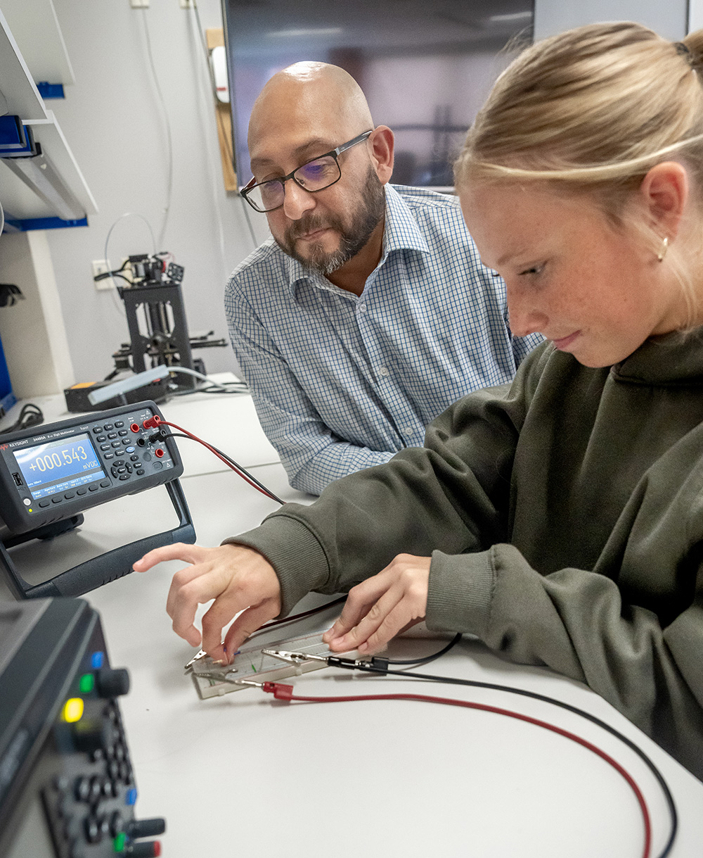 A faculty member working at a station with a student in the Electrical Engineering lab on the campus of Alma College.