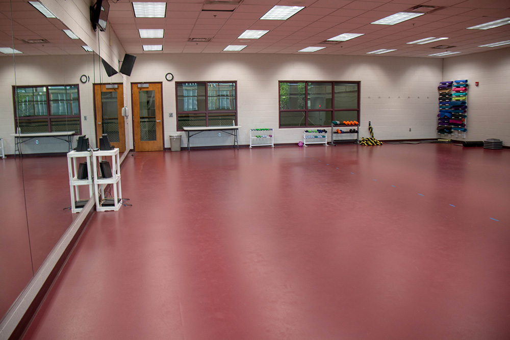 Multipurpose room photo showing mirrored wall, exercise equipment interior windows and door.