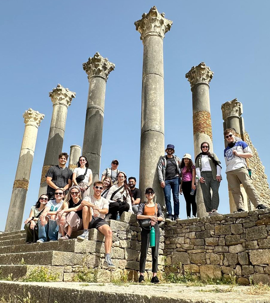 A class on sprint term standing in Morocco in front of an ancient colonnade.