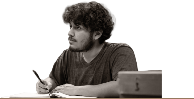 A student in class during lecture, listening and writing notes.