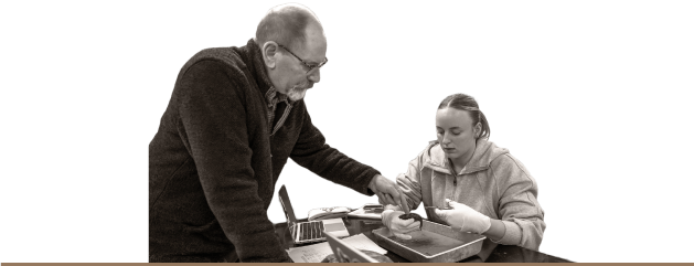 A professor helping a student during a dissection.