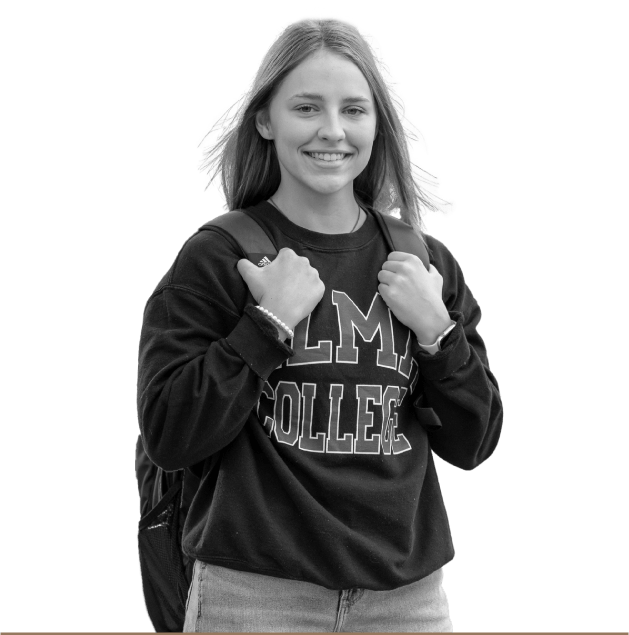 Portrait of a student looking at and smiling at the camera wearing an Alma College sweatshirt and a backpack.